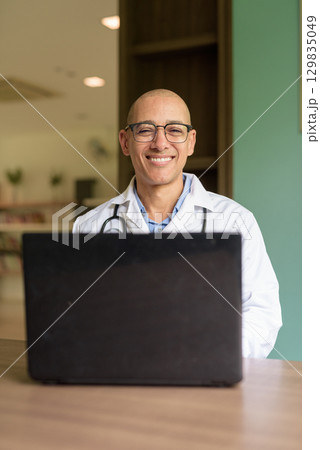 Doctor Sitting Indoors in Clinic or Hospital Area Library Using Laptop Computer Doctor Sitting Indoors in Clinic or Hospital Area Library Using Laptop Computer 129835049