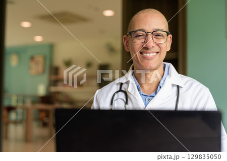 Doctor Sitting Indoors in Clinic or Hospital Area Library Using Laptop Computer Doctor Sitting Indoors in Clinic or Hospital Area Library Using Laptop Computer 129835050