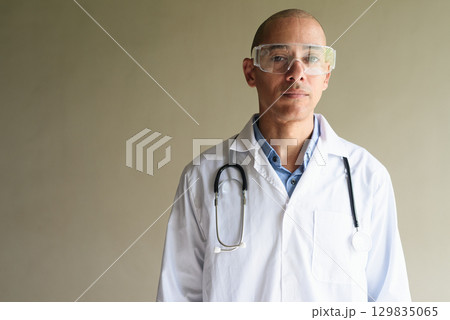 Male Scientist in Lab Coat with Safety Glasses on Plain Background 129835065