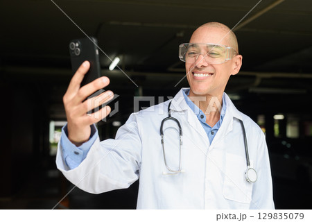 Bald Male Scientist Standing Outside Modern Research Facility Using Phone Bald Male Scientist Standing Outside Modern Research Facility Using Phone 129835079