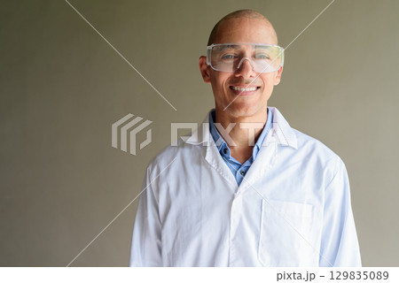 Male Scientist in Lab Coat with Safety Glasses on Plain Background 129835089