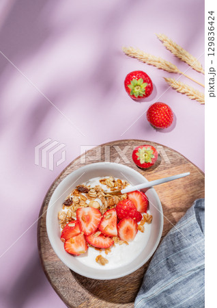 Granola or muesli with natural greek yogurt, strawberry in a bowl on a wooden board Granola or muesli with natural greek yogurt, strawberry in a bowl on a wooden board 129836424
