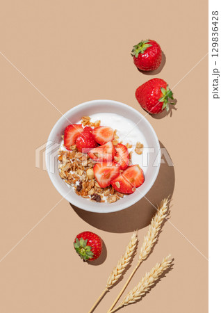 Granola or muesli with natural greek yogurt and strawberry in a bowl on a bright beige background Granola or muesli with natural greek yogurt and strawberry in a bowl on a bright beige background 129836428