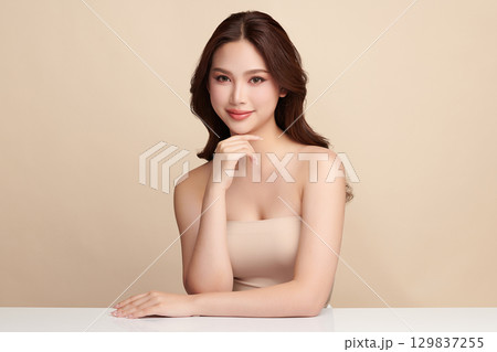 A beautiful young Asian woman with clean, fresh skin against a beige background. Skincare, facial treatment, cosmetology, beauty, and spa. An elegant portrait of an Asian woman. A beautiful young Asian woman with clean, fresh skin against a beige background. Skincare, facial treatment, cosmetology, beauty, and spa. An elegant portrait of an Asian woman. 129837255