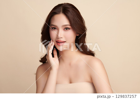 A beautiful young Asian woman with clean, fresh skin against a beige background. Skincare, facial treatment, cosmetology, beauty, and spa. An elegant portrait of an Asian woman. A beautiful young Asian woman with clean, fresh skin against a beige background. Skincare, facial treatment, cosmetology, beauty, and spa. An elegant portrait of an Asian woman. 129837257