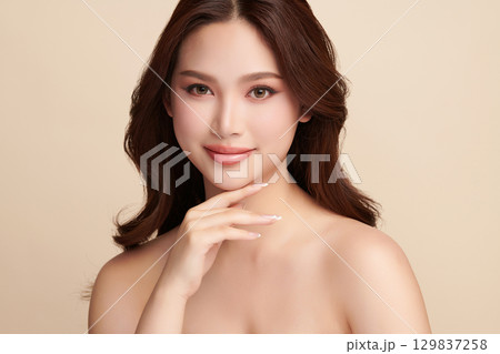 A beautiful young Asian woman with clean, fresh skin against a beige background. Skincare, facial treatment, cosmetology, beauty, and spa. An elegant portrait of an Asian woman. A beautiful young Asian woman with clean, fresh skin against a beige background. Skincare, facial treatment, cosmetology, beauty, and spa. An elegant portrait of an Asian woman. 129837258