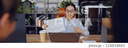 A skilled and professional woman is giving a presentation of data in a modern office environment A skilled and professional woman is giving a presentation of data in a modern office environment 129838663