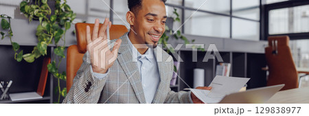 A Professional Man Actively Engaging in a Virtual Meeting Set in a Modern Office Space 129838977