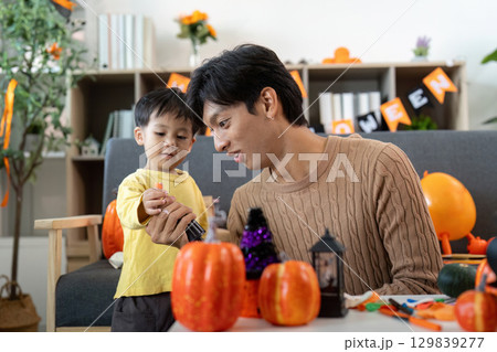 Halloween Fun. Father and son crafting pumpkin decorations at home. Halloween Fun. Father and son crafting pumpkin decorations at home. 129839277