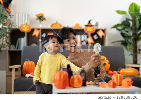 Halloween Joy. Father and son sharing a playful moment with pumpkin decorations. Halloween Joy. Father and son sharing a playful moment with pumpkin decorations. 129839320
