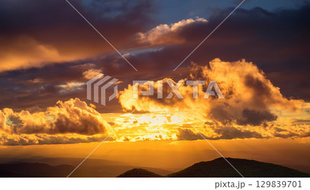 Golden sunset clouds illuminating sky with warmth and positive energy Golden sunset clouds illuminating sky with warmth and positive energy 129839701