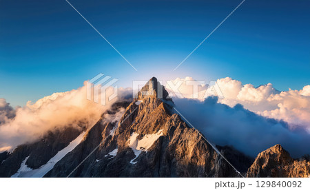 Majestic mountain peak piercing clouds under vivid sky, symbolizing power 129840092
