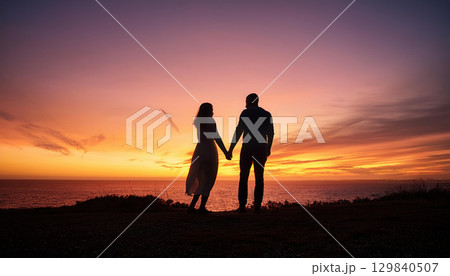 romantic silhouette of couple holding hands at sunset by ocean 129840507
