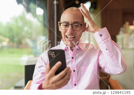 Stressed man using phone in coffee shop having headache 129841195