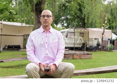 Bald Hispanic man wearing pink casual business shirt and eyeglasses outdoors 129841232