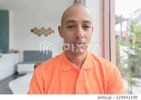 Bald Hispanic man face inside cafe restaurant wearing orange polo shirt Bald Hispanic man face inside cafe restaurant wearing orange polo shirt 129841290