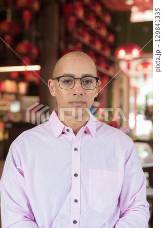 Bald Hispanic man wearing pink casual business shirt and eyeglasses in Chinese style tea house 129841335
