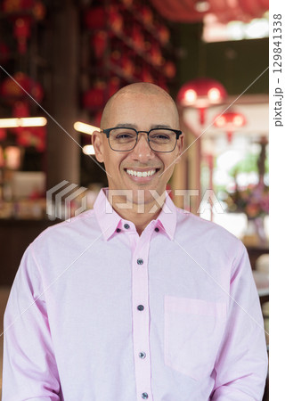 Bald Hispanic man wearing pink casual business shirt and eyeglasses in Chinese style tea house 129841338