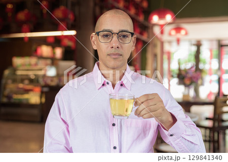 Bald Hispanic man wearing pink casual business shirt and eyeglasses in Chinese style tea house 129841340