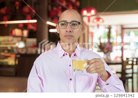 Bald Hispanic man wearing pink casual business shirt and eyeglasses in Chinese style tea house Bald Hispanic man wearing pink casual business shirt and eyeglasses in Chinese style tea house 129841342