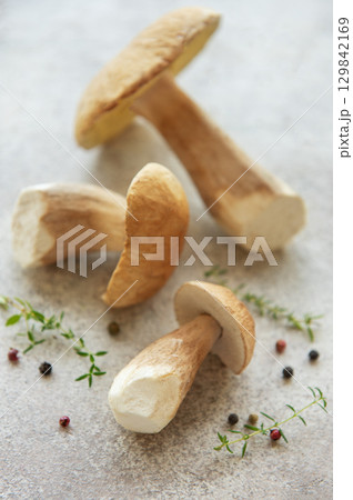Fresh porcini mushrooms with thyme and peppercorns on gray background 129842169