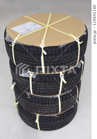 通信販売サイトで注文したホイール付きの冬用スタッドレスタイヤが段ボールで保護された荷姿で到着した場面 129842186