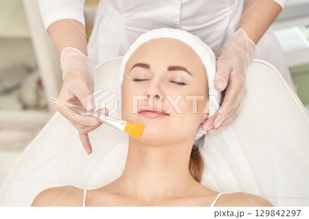 Female caucasian adult receiving facial treatment at spa with relaxed expression 129842297