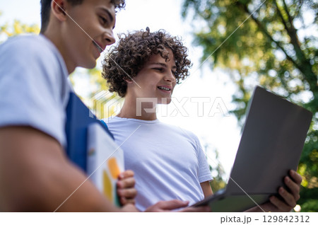 Teens in the park with laptop and books preparing for the lessons 129842312
