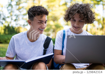 Teens in the park with laptop and books preparing for the lessons 129842314