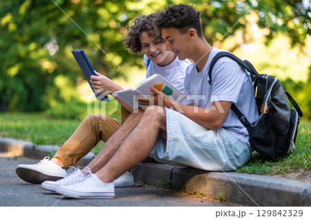 Two teens reading books together and looking enjoyed Two teens reading books together and looking enjoyed 129842329