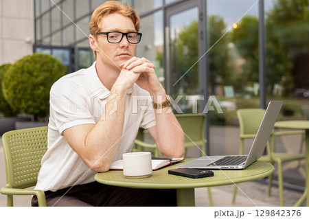 Ginger remote worker touching face thinking planning next steps 129842376