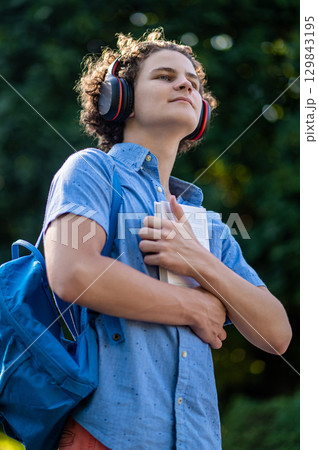 Curly-haired teen with a book in hands in the park 129843195