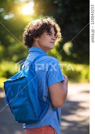 Curly-haired teen in blue tshirt spending time in the park 129843253