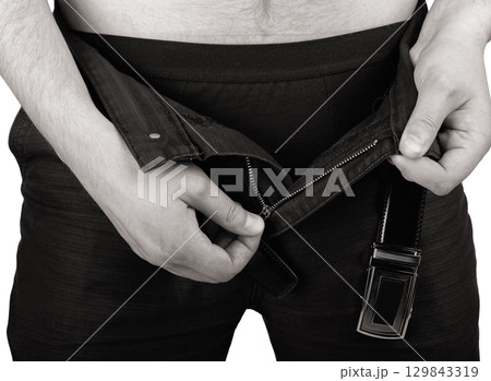 Hands of a man unzips his fly of their pants 129843319