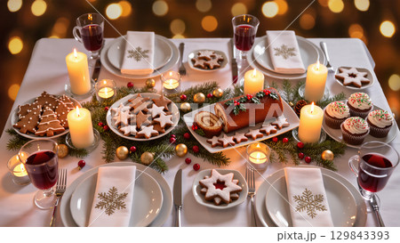 Christmas dessert table setting with cookies, cake, cupcakes, candles and mulled wine, festive and cozy holiday celebration scene 129843393