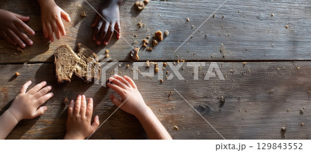 Children joyfully sharing tasty food on a wooden table, creating a vibrant, happy atmosphere 129843552