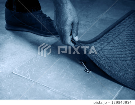 A person getting a key from under their mat A person getting a key from under their mat 129843954