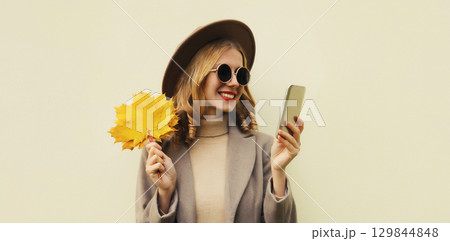 Autumn portrait stylish happy smiling young woman with phone, beautiful girl holding yellow leaves Autumn portrait stylish happy smiling young woman with phone, beautiful girl holding yellow leaves 129844848