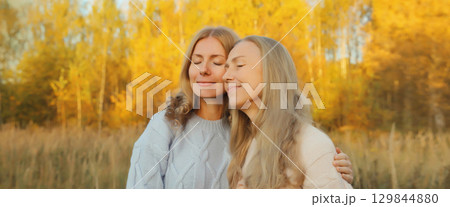 Happy two women, smiling mature mother and adult daughter hugging in autumn park 129844880