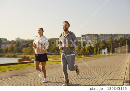 Young happy couple running in the park having sport workout together outdoors. 129845126