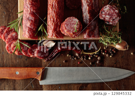 Sliced dry cured sausages with peppercorns, thyme, rosemary, and garlic. Sliced dry cured sausages with peppercorns, thyme, rosemary, and garlic. 129845332