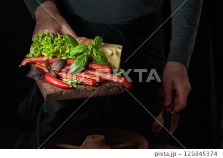Thin smoked sausages with cheese, bread, and greens. Thin smoked sausages with cheese, bread, and greens. 129845374
