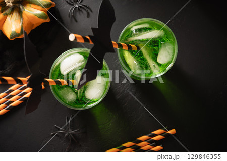 Halloween green cocktail garnish black bat on black background. Festive drink and playful holiday decoration. View from above 129846355