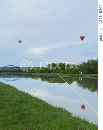 Hot air balloons flying over a water canal 129846560