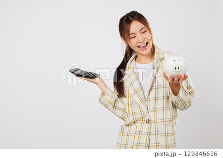 Businesswoman with white piggy bank and calculator reviewing budget, then double-checks using another calculator for accuracy in finance and banking strategy. isolated studio white background 129846616