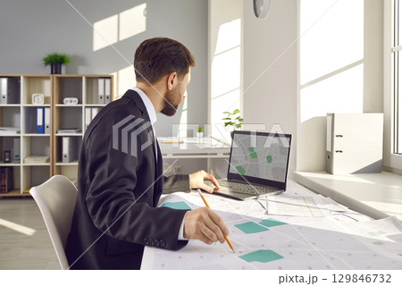 Cadastral surveyor is working with cadastral city maps and using a laptop computer Cadastral surveyor is working with cadastral city maps and using a laptop computer 129846732