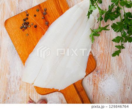 Raw halibut fillet on wooden table 129846764