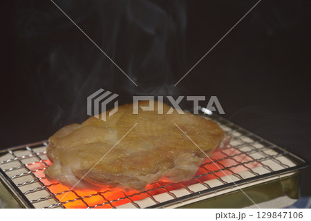 煙りの立ち昇る七輪で鶏モモ肉を焼く 煙りの立ち昇る七輪で鶏モモ肉を焼く 129847106