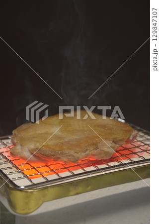 煙りの立ち昇る七輪で鶏モモ肉を焼く 煙りの立ち昇る七輪で鶏モモ肉を焼く 129847107