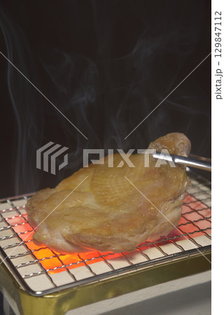 煙りの立ち昇る七輪で鶏モモ肉を焼く 煙りの立ち昇る七輪で鶏モモ肉を焼く 129847112